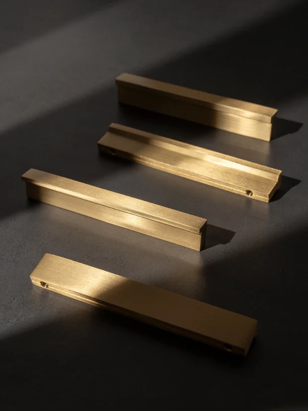 Four gold rectangular objects on a dark surface