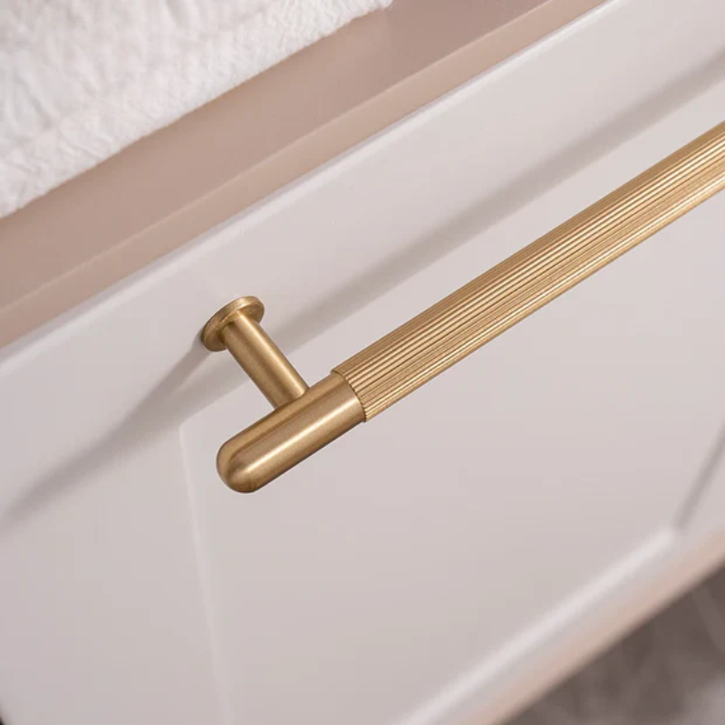Gold cabinet handle on a white drawer