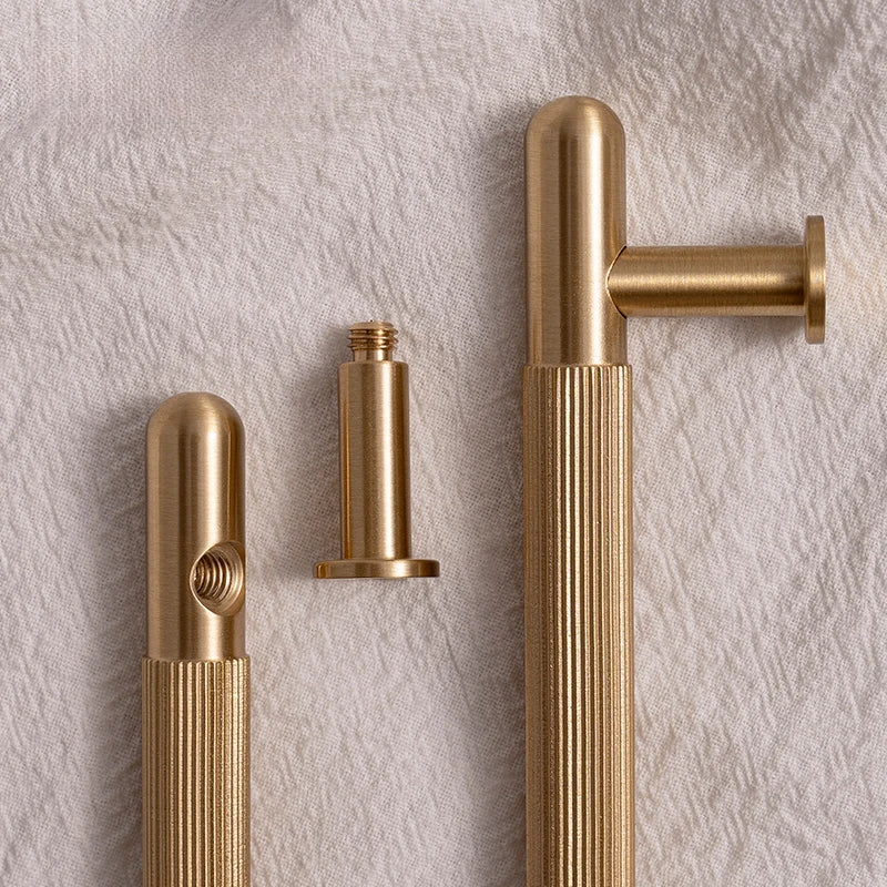 Three gold door handles on a textured beige wall