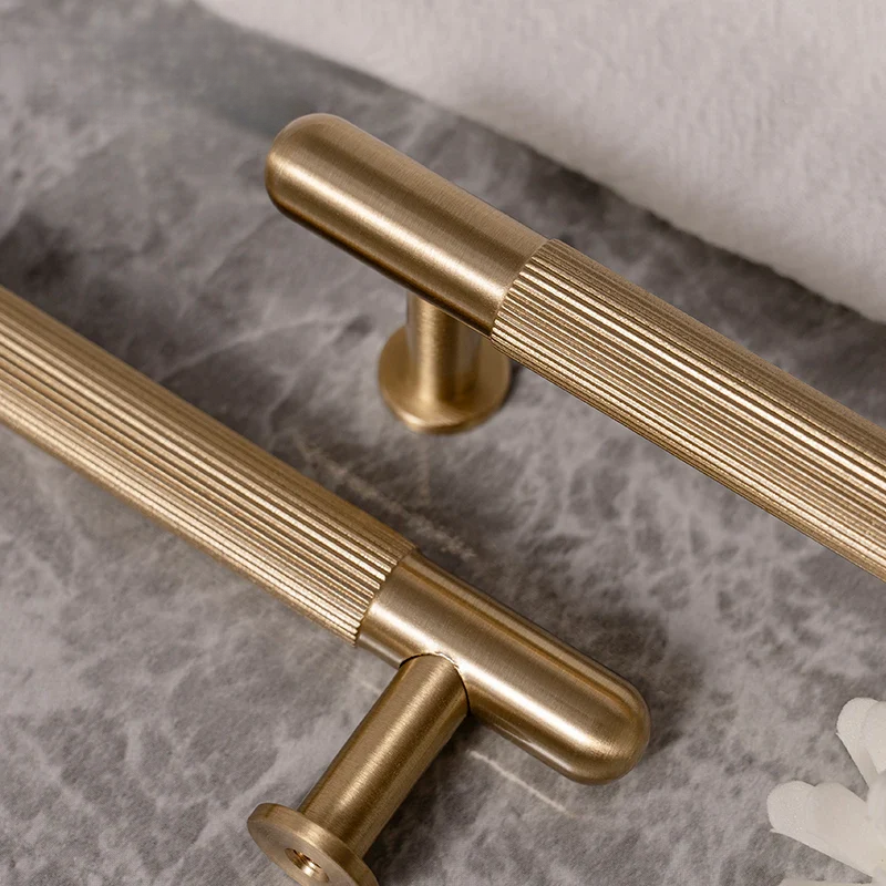 Two gold cabinet handles on a marble surface