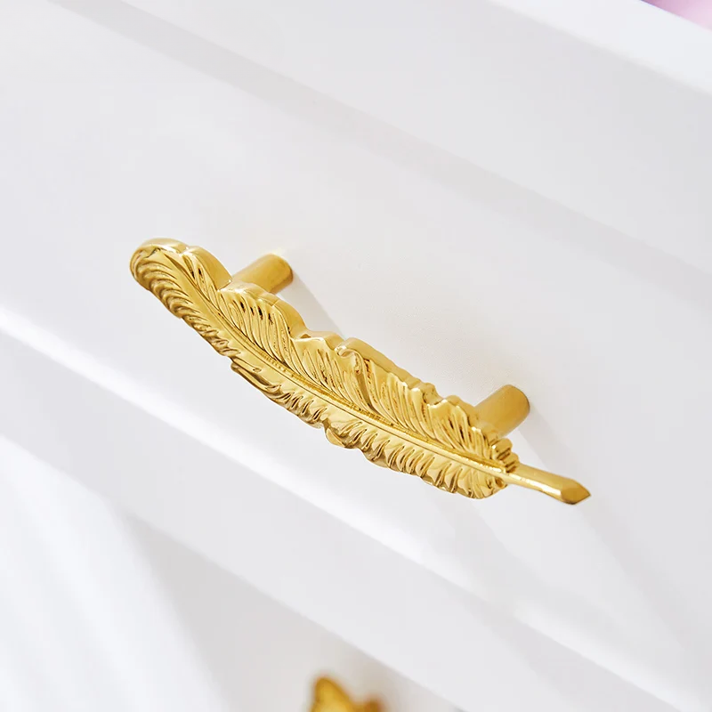 Gold feather-shaped handle on a white surface
