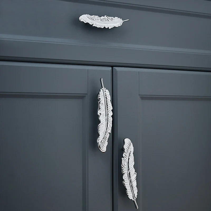 Decorative feather cabinet knobs on a dark gray cabinet.