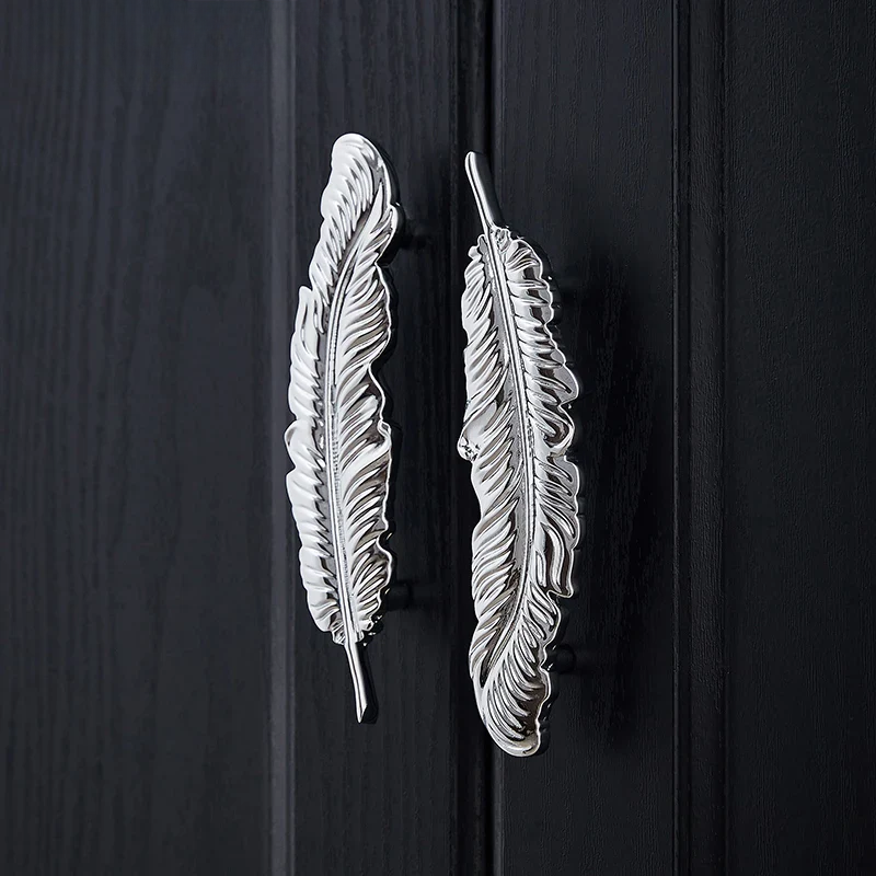 Feather-shaped silver door handles on a black wooden door