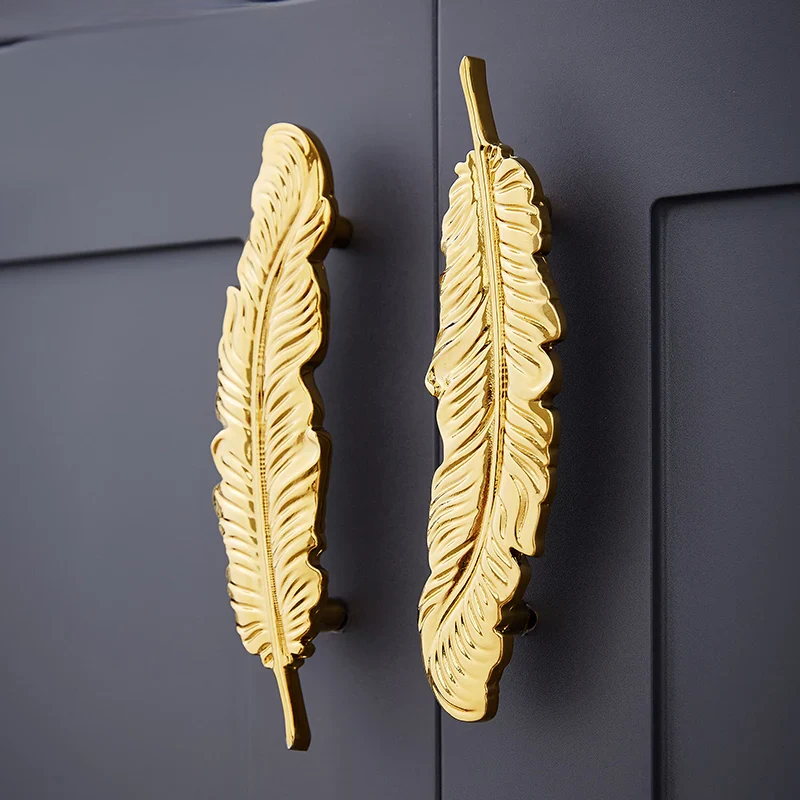 Gold feather-shaped handles on a dark gray cabinet.