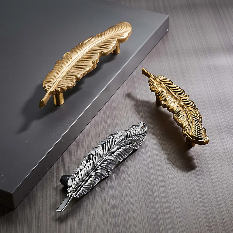 Gold and silver feather-shaped handles on a wooden surface