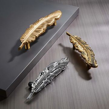 Gold and silver feather-shaped handles on a wooden surface