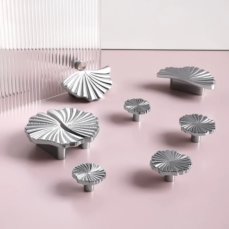 Set of silver cabinet knobs with decorative patterns on a pink background