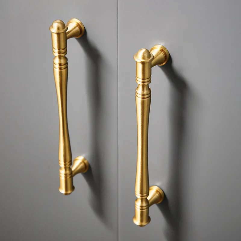 Pair of gold cabinet handles on a gray background