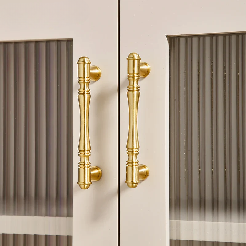 Gold cabinet handles on a door with a neutral background