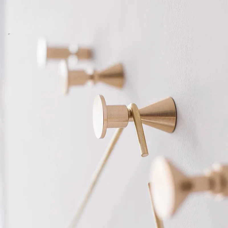 Gold wall-mounted shower control handles on a white wall