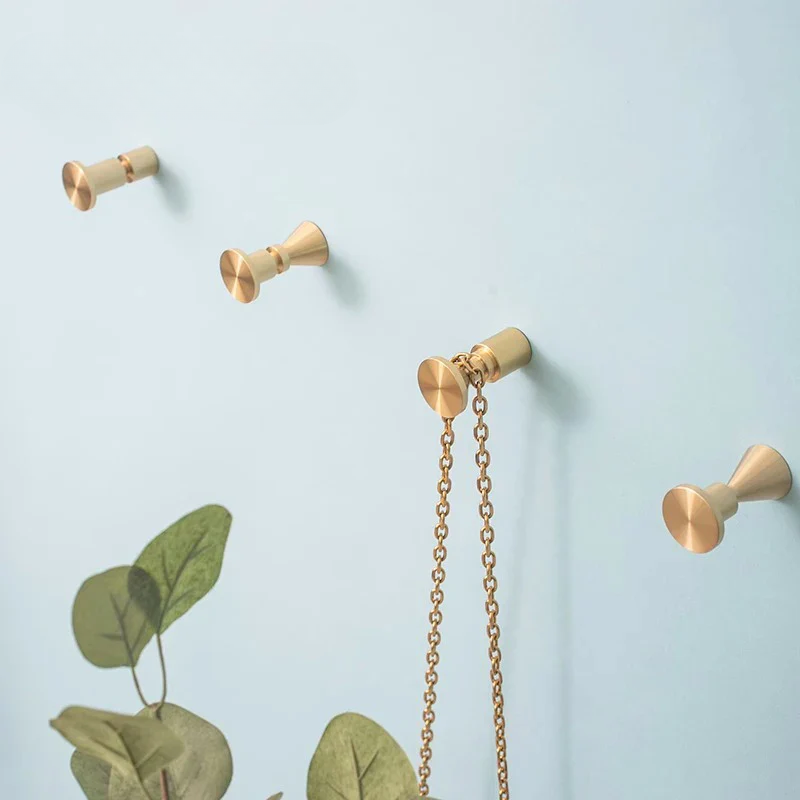 Set of gold wall hooks with a chain on a light blue background