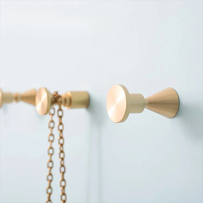 Gold curtain rod with decorative finial and chain on a light blue background
