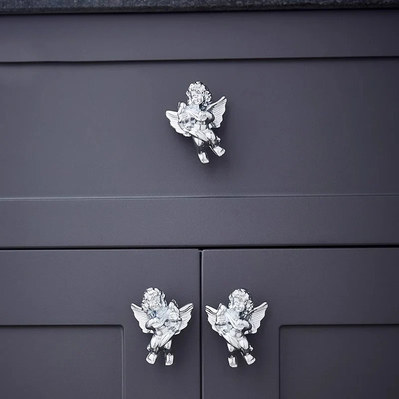 Decorative angel knobs on a dark gray cabinet