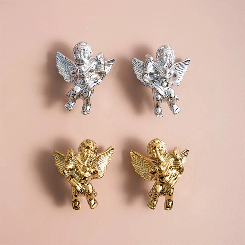 Four angel figurines in gold and silver on a pink background