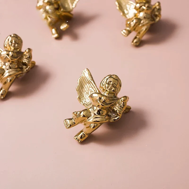 Four angel figurines in gold and silver on a pink background
