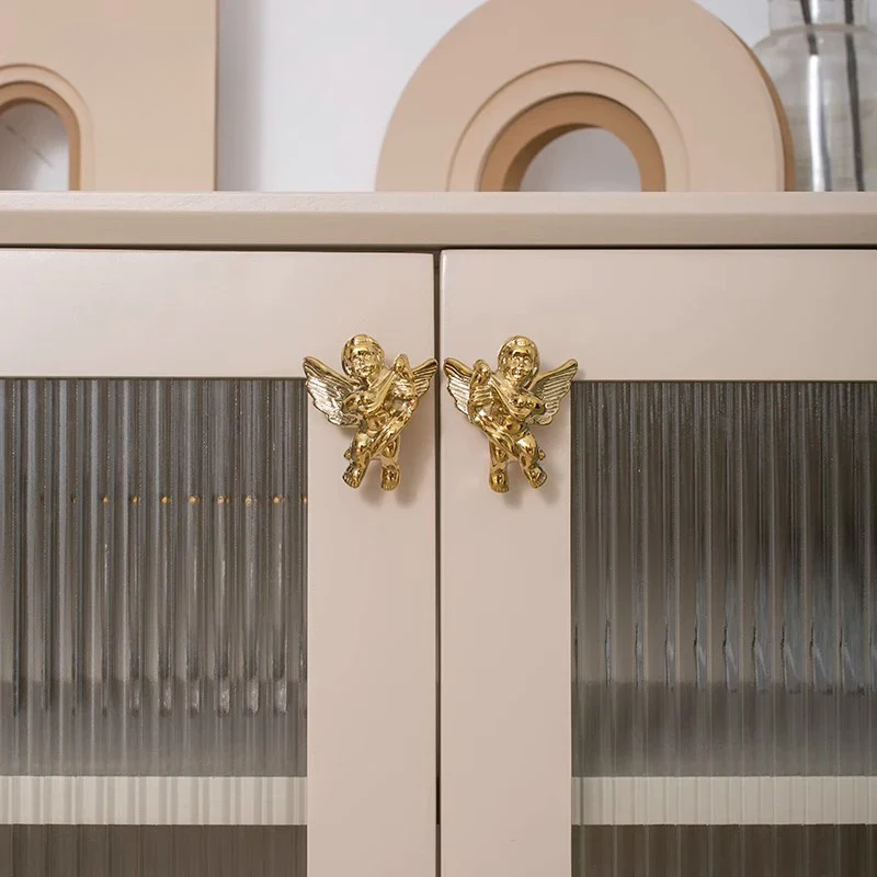 Cabinet with gold angel-shaped handles on a neutral background
