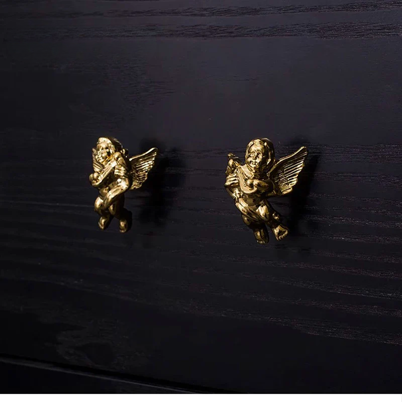 Gold angel earrings on a dark wooden surface