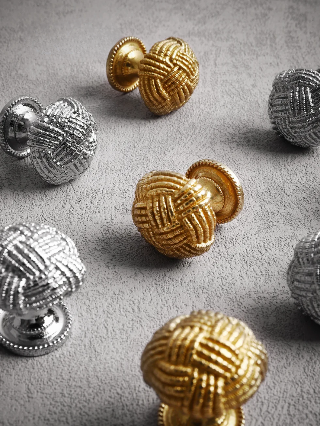Decorative door knobs in gold and silver on a gray surface