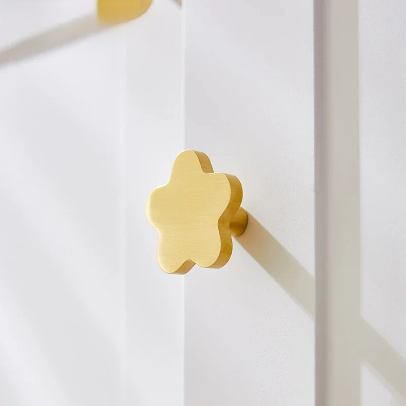 Gold flower-shaped door handle on a white door