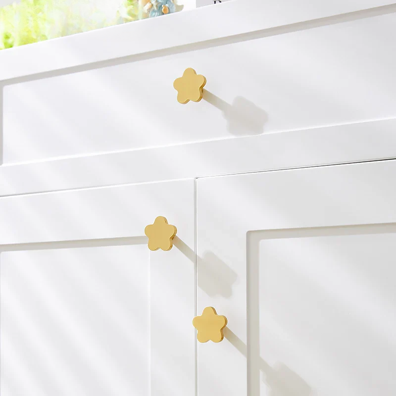 White cabinet with gold flower-shaped handles on a blurred background