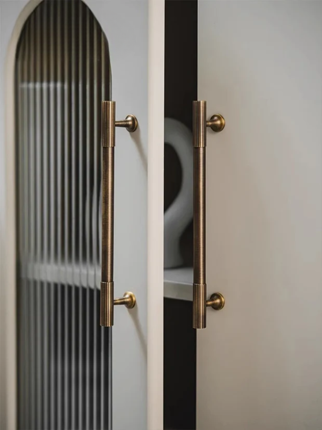 Close-up of a cabinet with gold handles on a neutral background