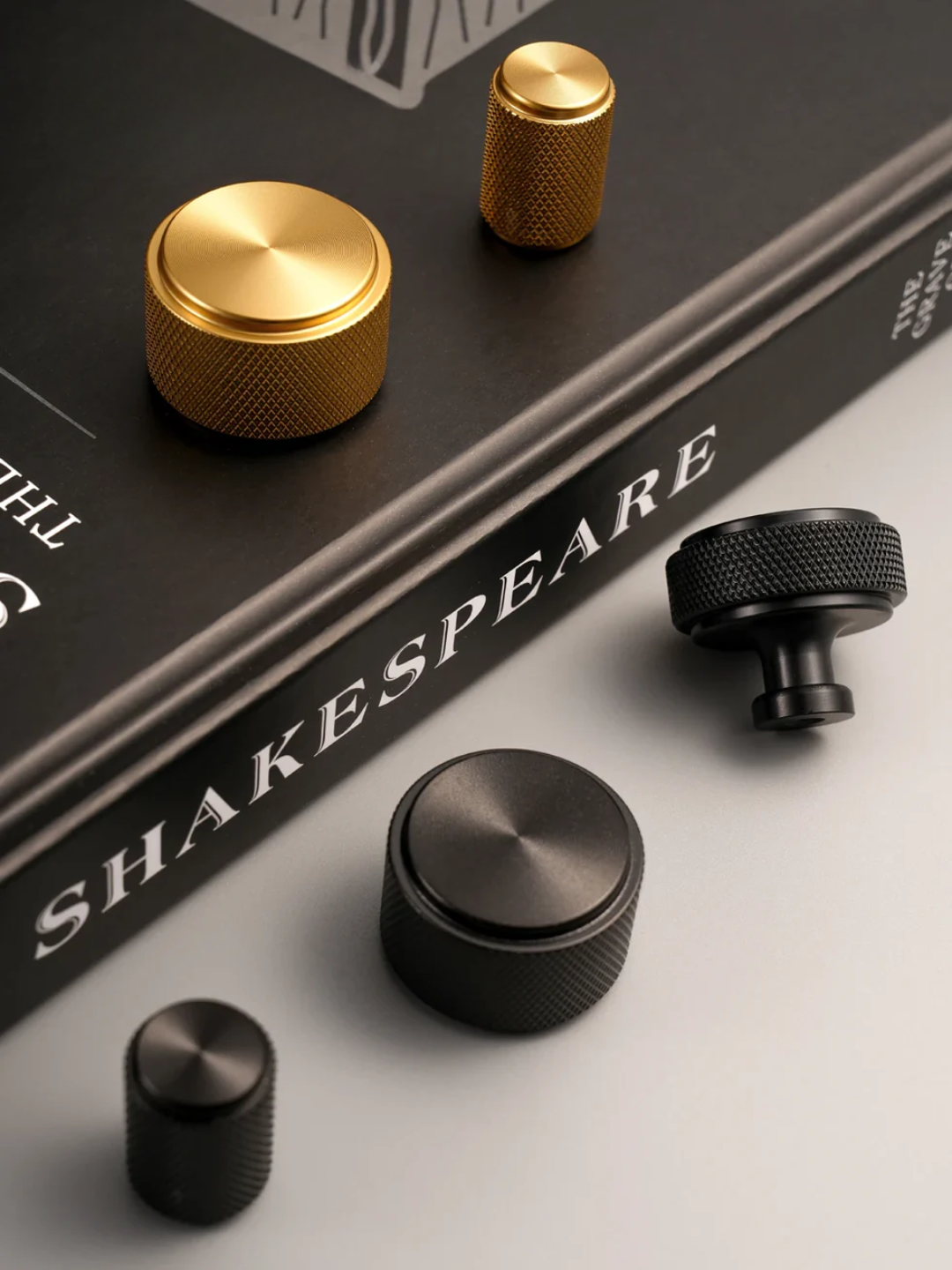 Gold and black knobs on a book titled 'Shakespeare' with a white background
