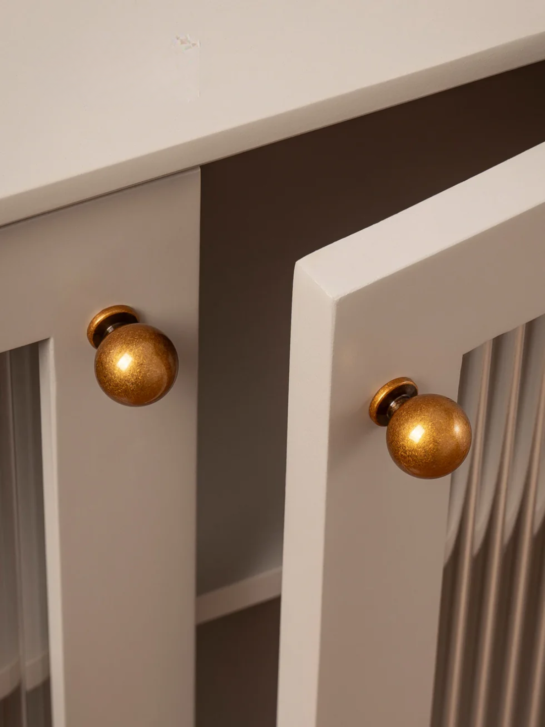 Close-up of gold spherical light fixtures on a white wall.