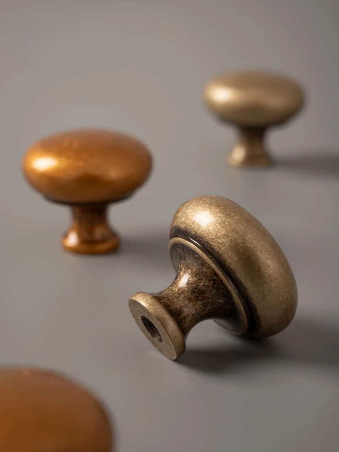 Brass cabinet knobs on a stone surface with a gray background