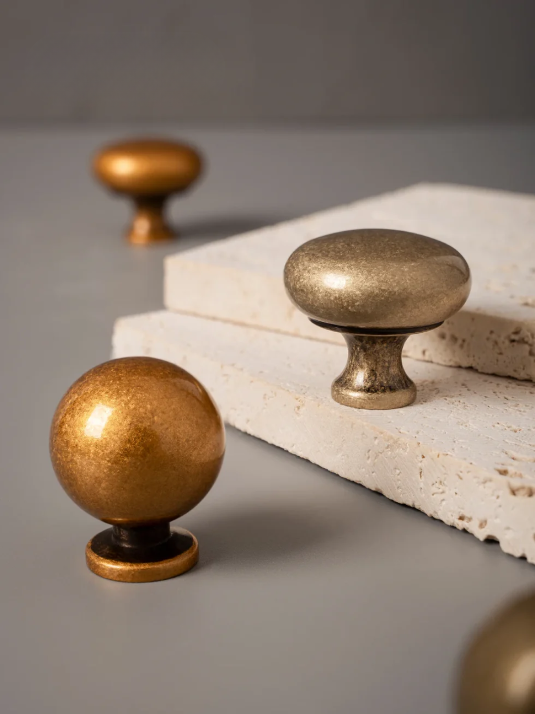 Brass cabinet knobs on a stone surface with a gray background
