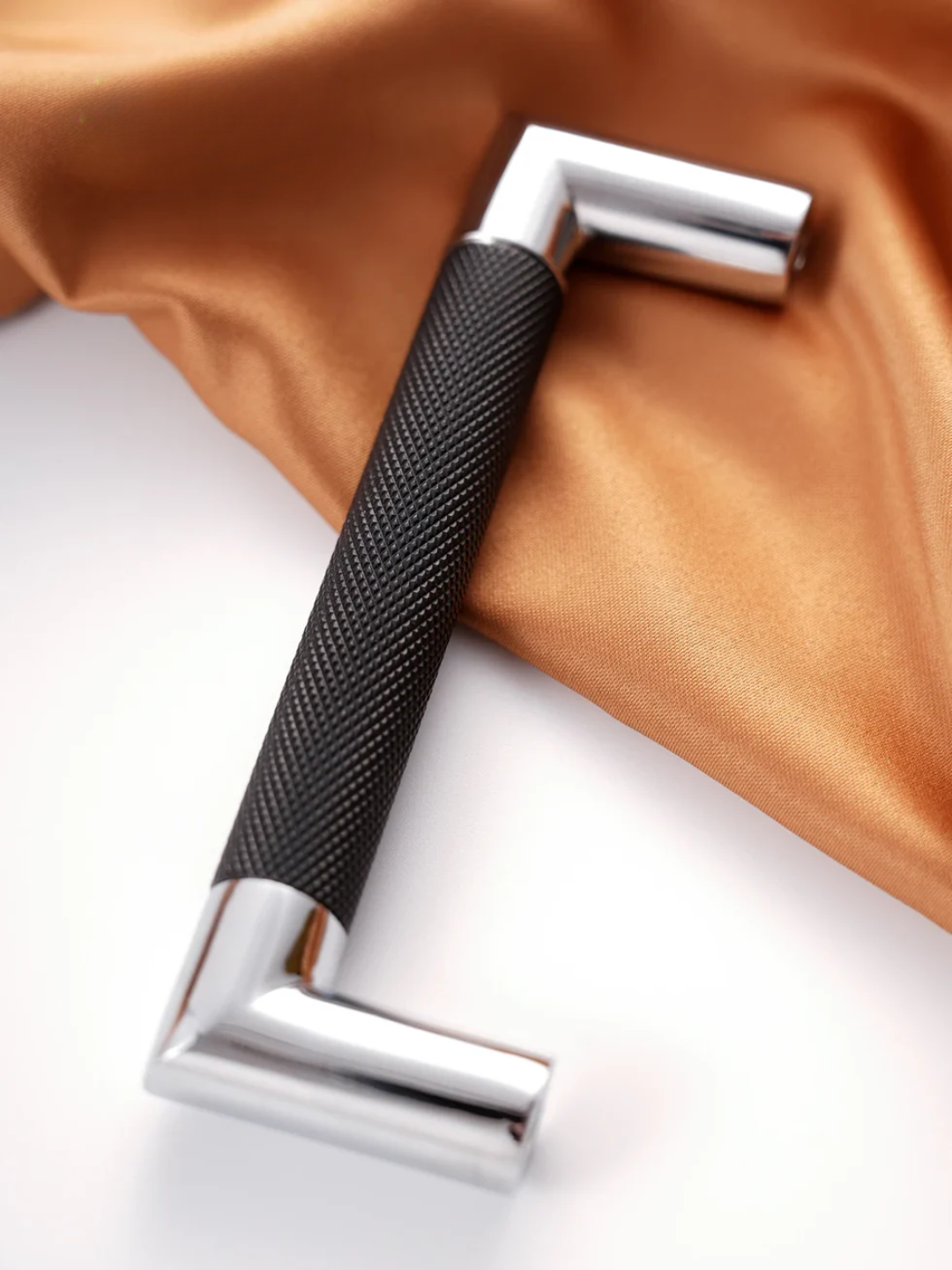 Close-up of a black textured handle and silver metal bracket on a brown fabric background