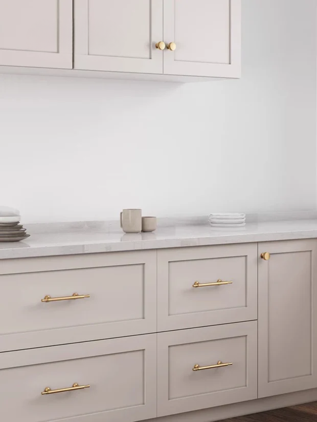 Gray kitchen cabinets with gold handles and a white countertop.