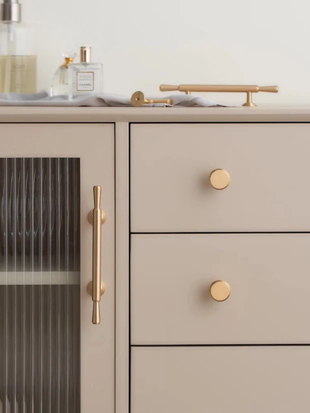 Beige kitchen cabinet with gold handles and a white background