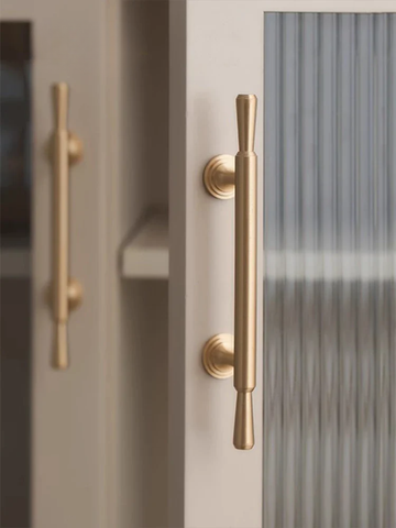 Close-up of a door with gold handles and a blurred background