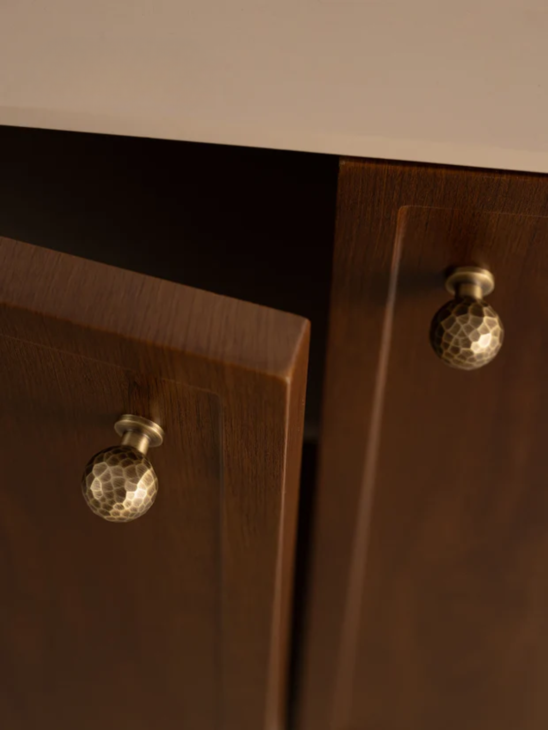 Close-up of wooden furniture with decorative knobs on a neutral background