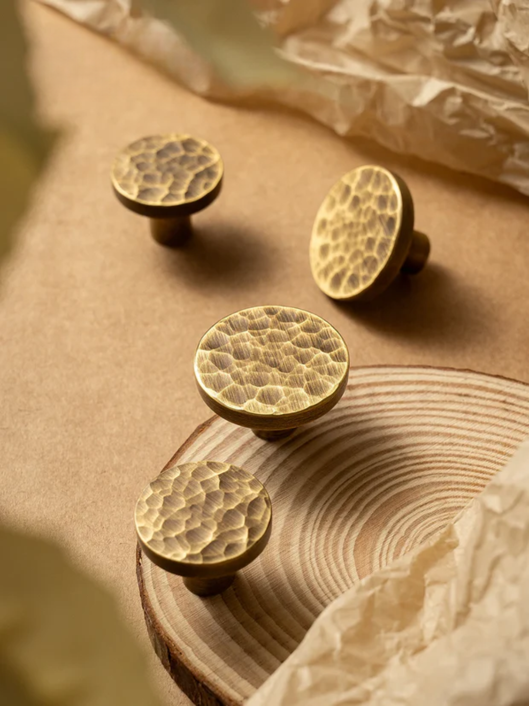 Four gold cabinet knobs with a textured surface on a wooden surface.