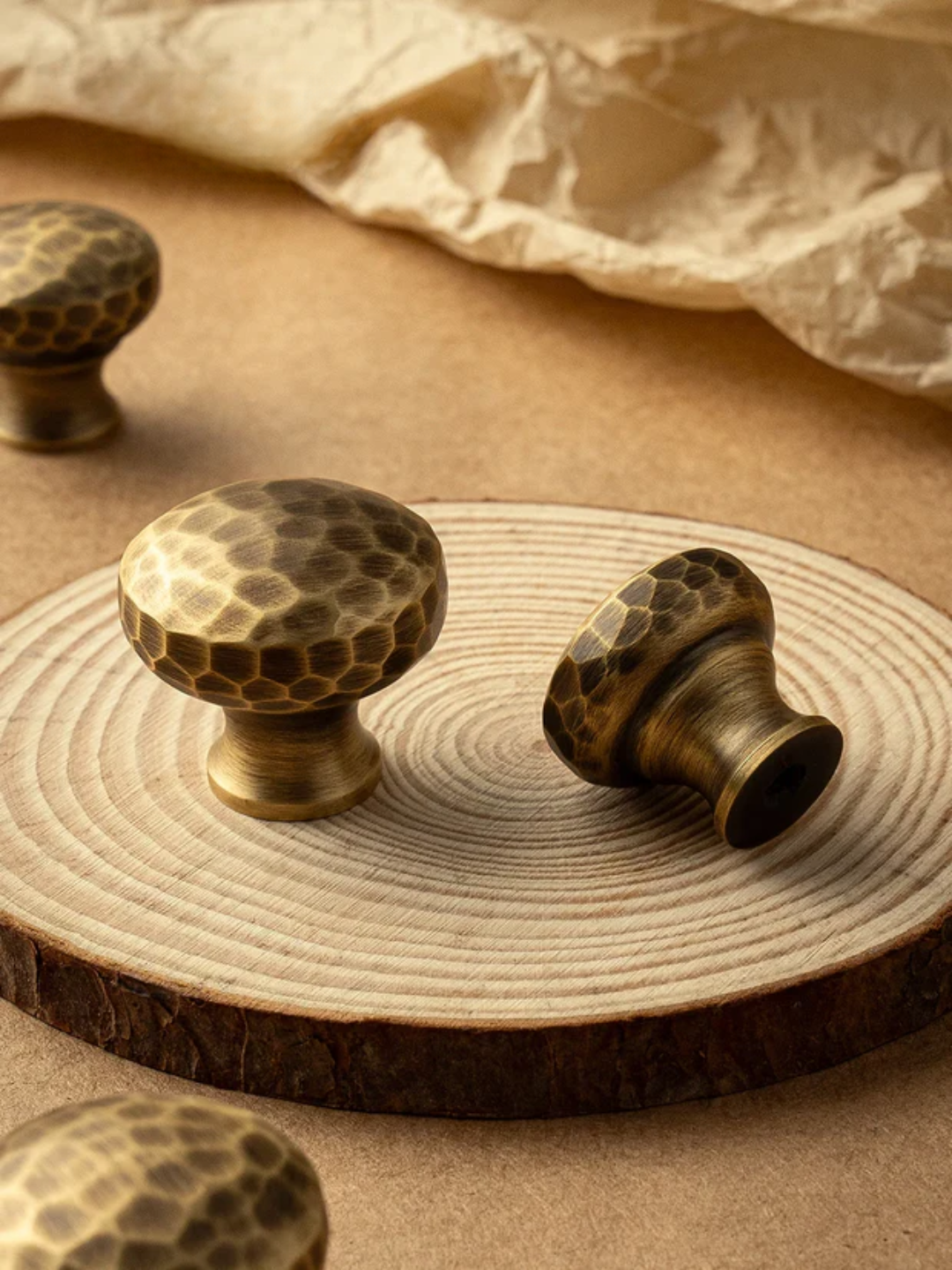 Decorative bronze knobs on a wooden surface with a beige fabric background