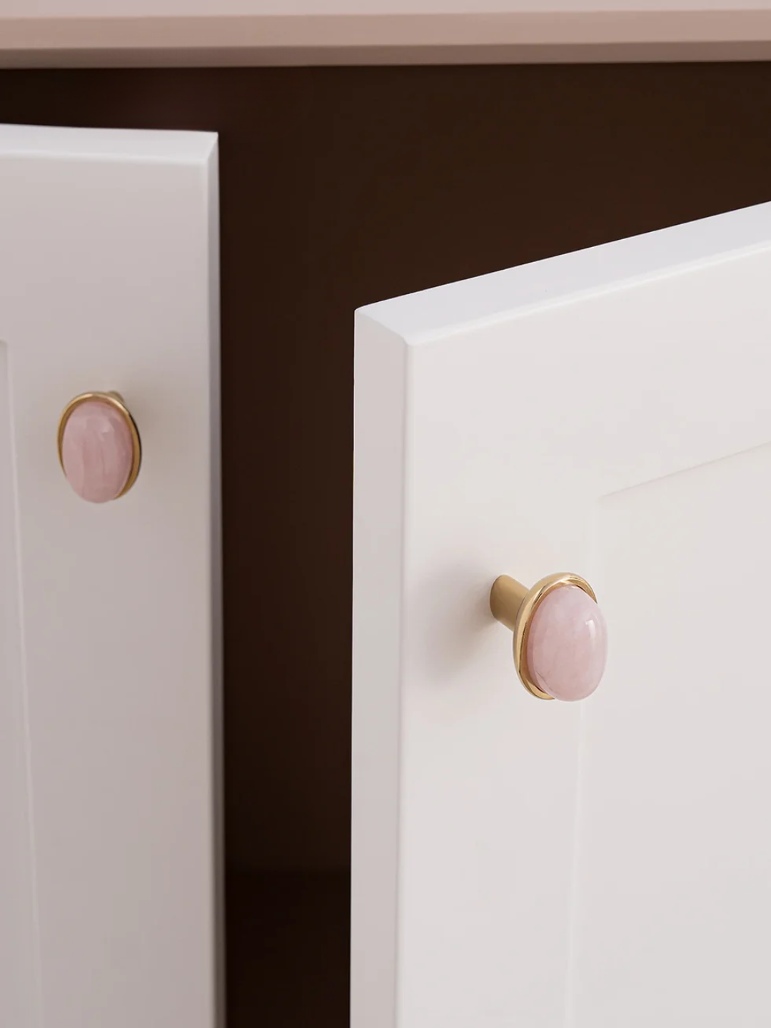 Close-up of white cabinets with pink knobs on a dark background