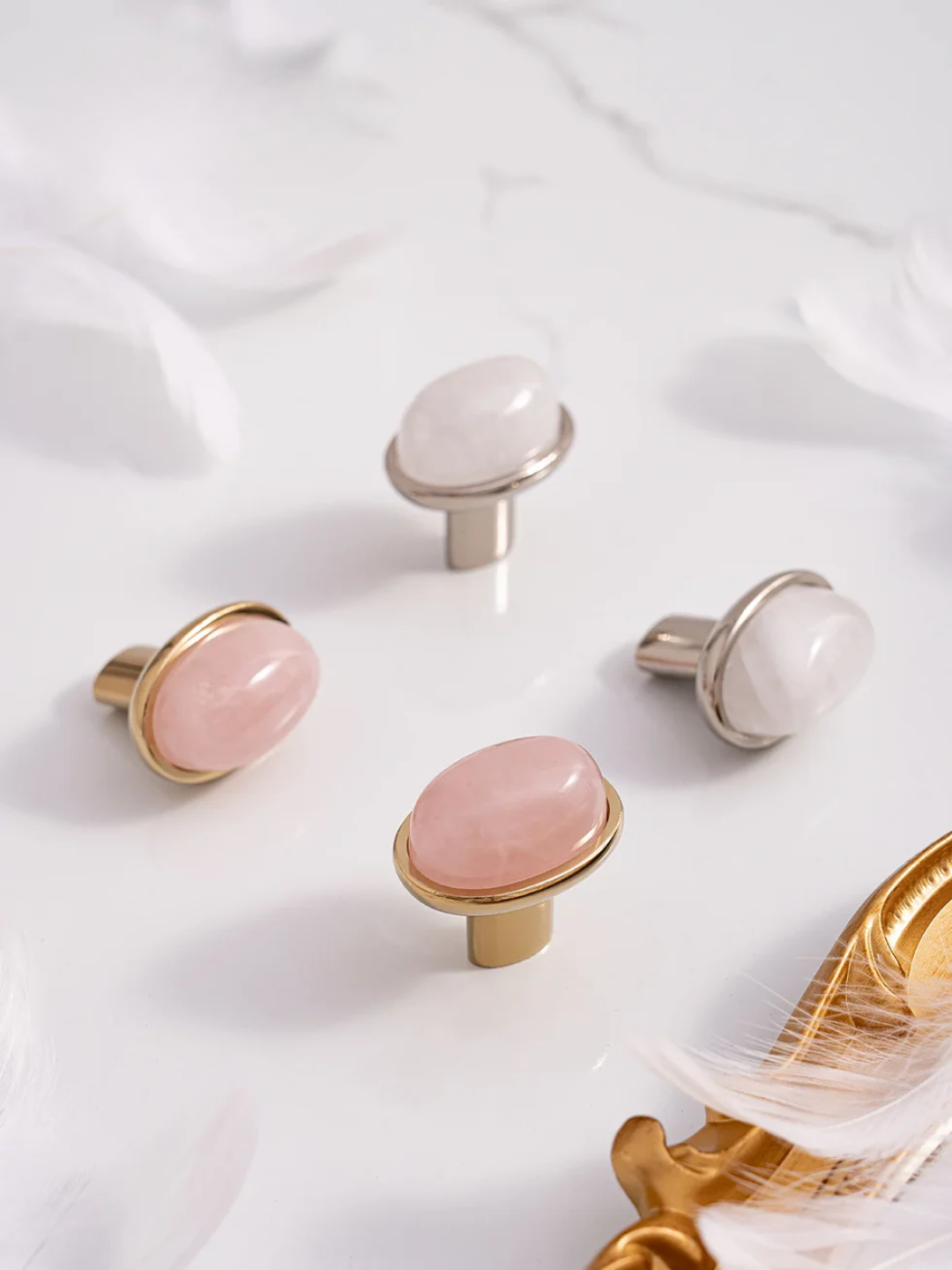 Set of decorative knobs with pink and white stones on a white fabric background