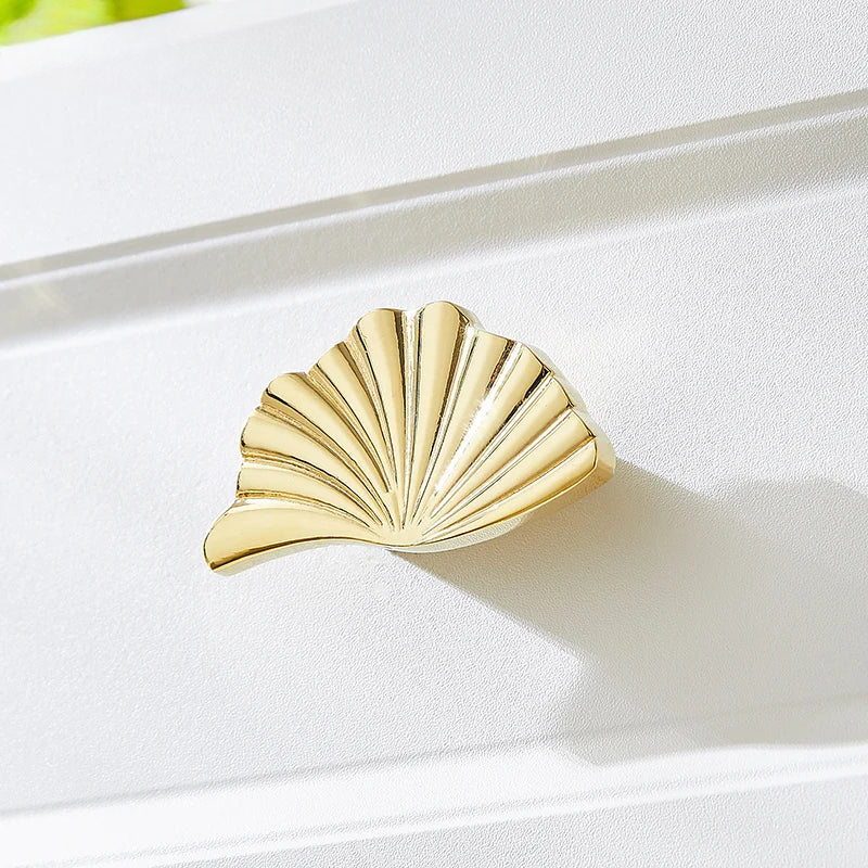 Gold shell-shaped jewelry on a white surface
