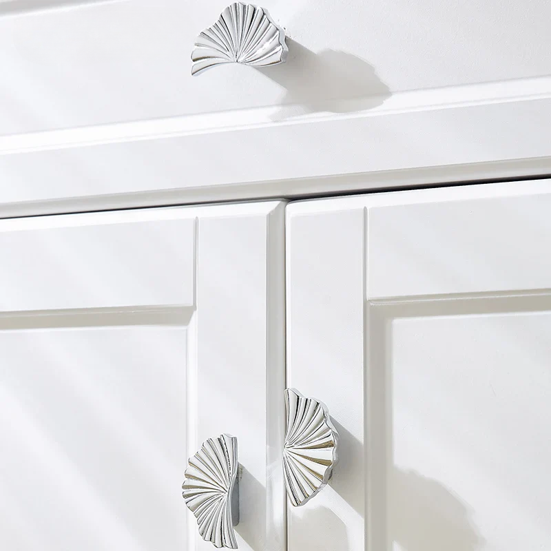 Close-up of white cabinet doors with decorative silver handles on a white background