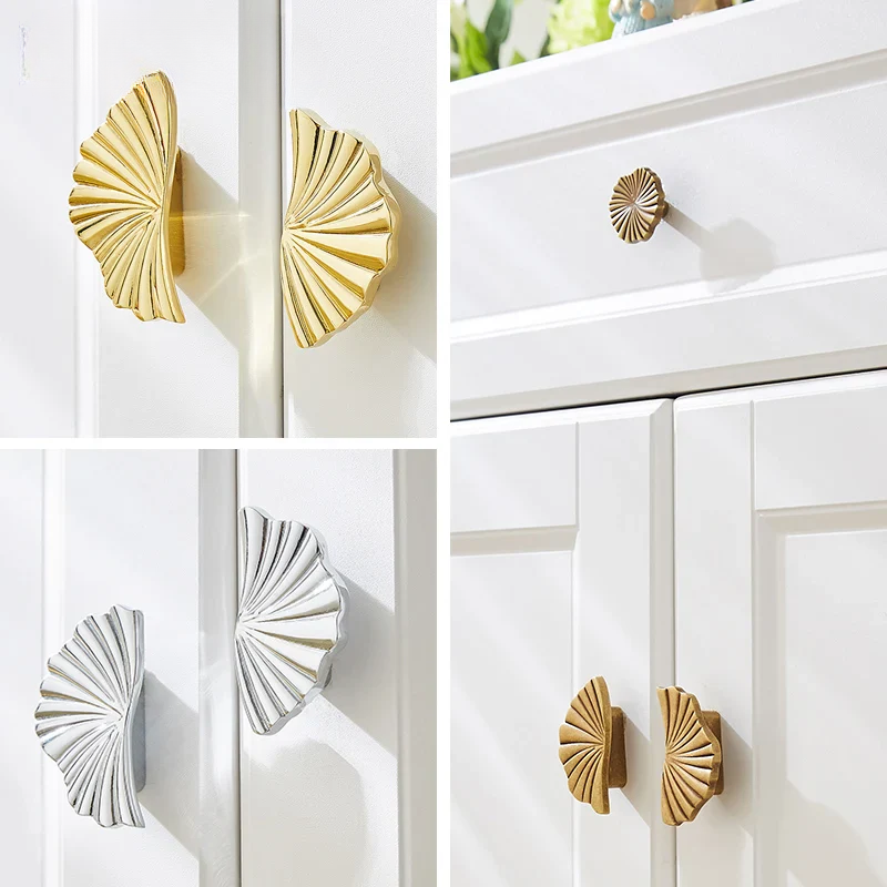 Decorative cabinet handles in gold and silver on white cabinets.