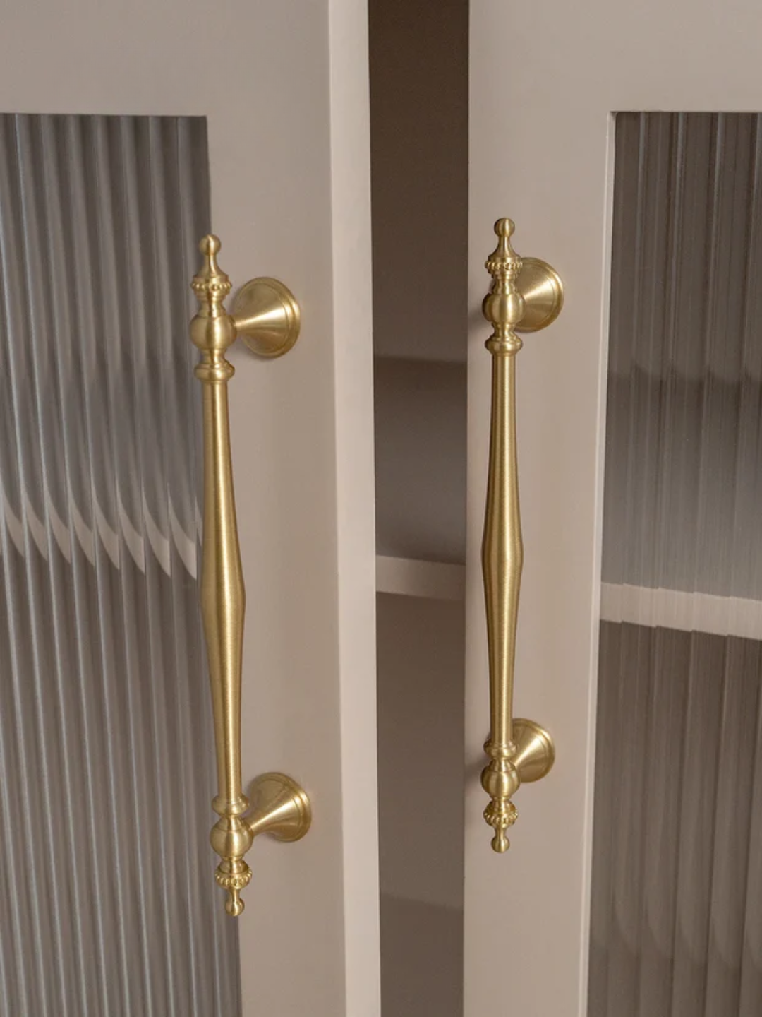 Gold cabinet handles on a door with a neutral background