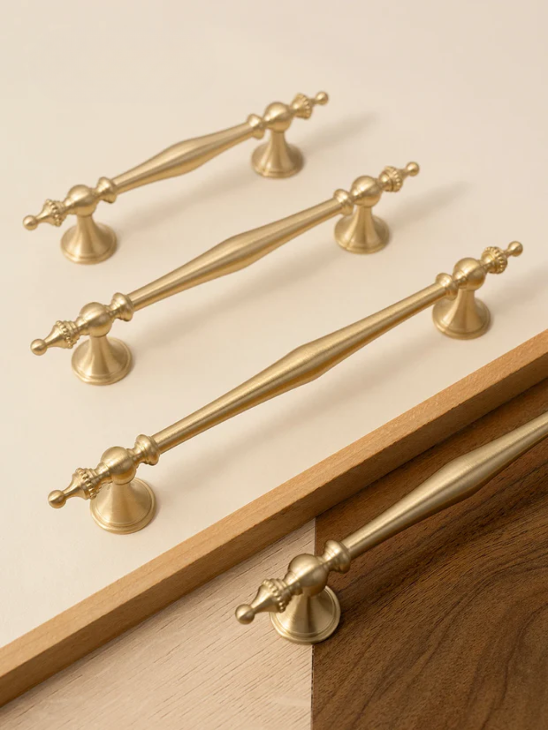 Collection of gold cabinet handles and knobs on a beige background