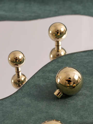 Gold spherical door handles on a green and white door.
