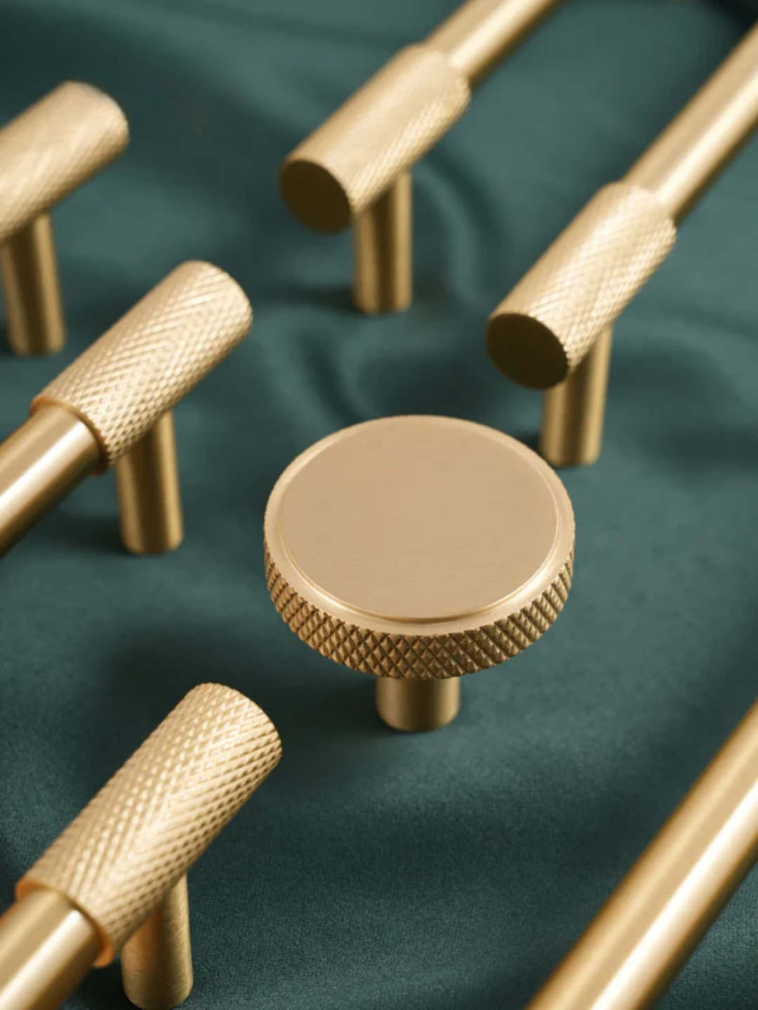 Gold cabinet knobs on a green fabric background