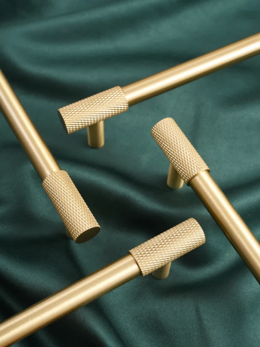 Gold cabinet knobs on a green fabric background