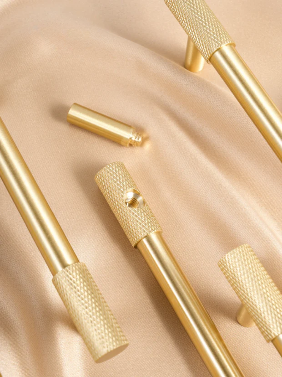 Gold-colored tools with textured handles on a beige fabric background