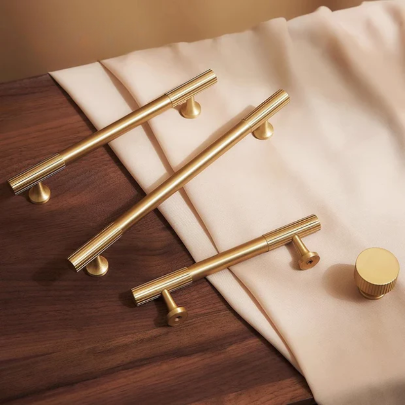 Gold cabinet handles on a wooden surface with a beige fabric background