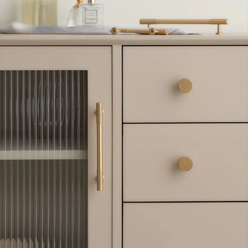 Beige cabinet with gold handles and knobs on a neutral background