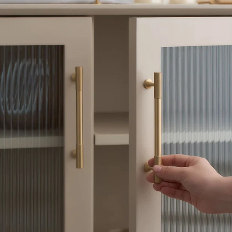 Hand opening a cabinet door with gold handle